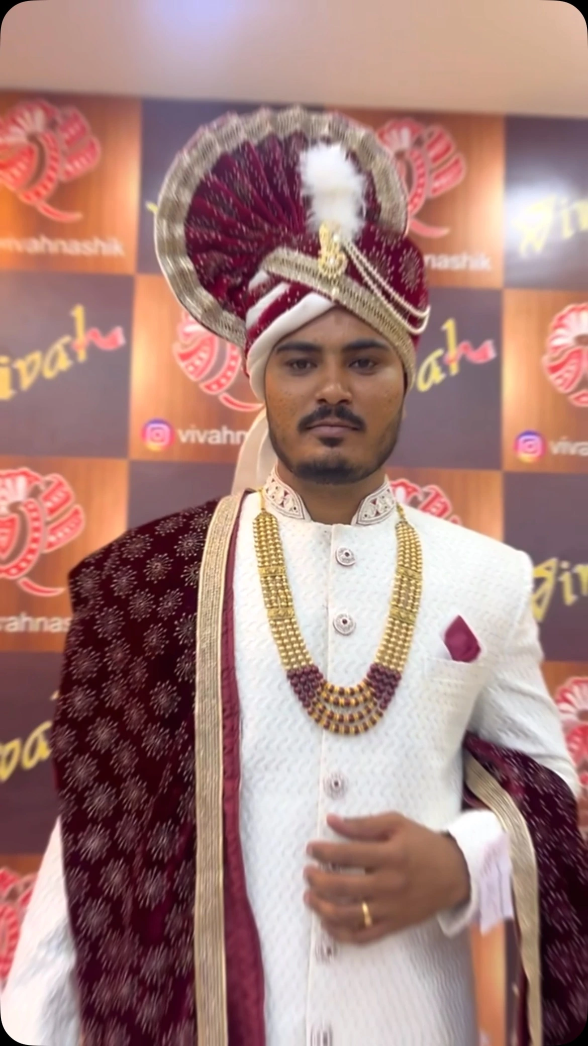 Vivah groom wearing white sherwani, maroon velvet stole and royal safa